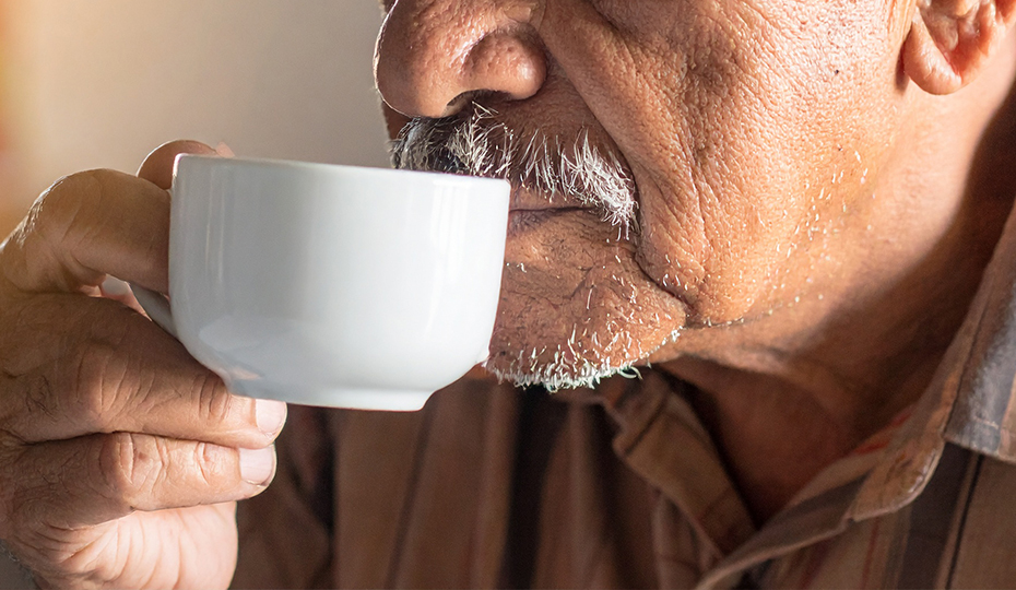 カップで飲み物を飲む老人