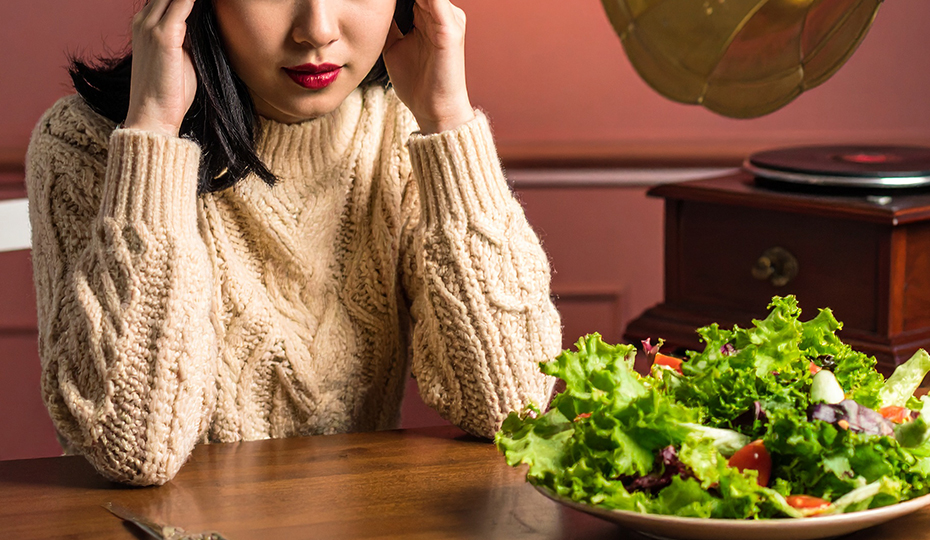 蓄音機やサラダの前で頭を抱える女性