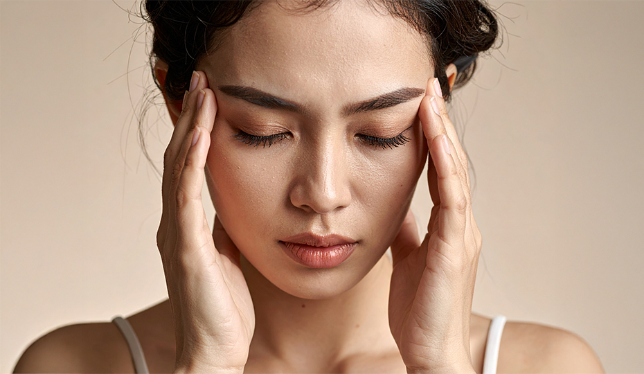 頭痛で頭を押さえている女性