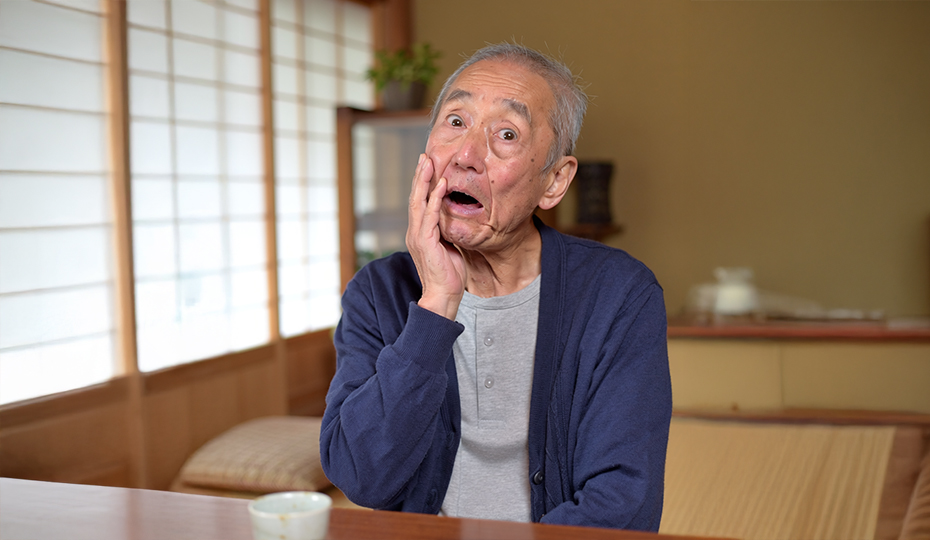 驚いた表情で自分の顔を触る男性