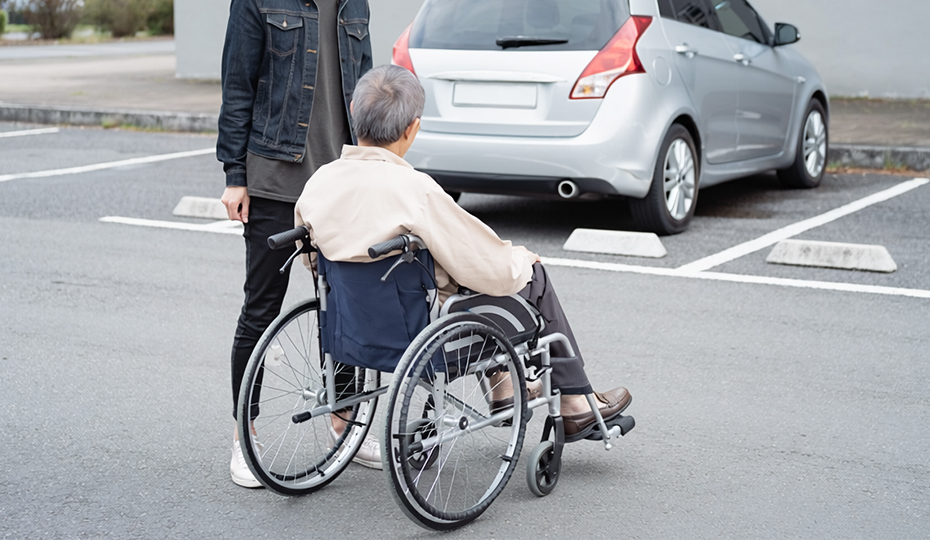 駐車場にいる車椅子の老人