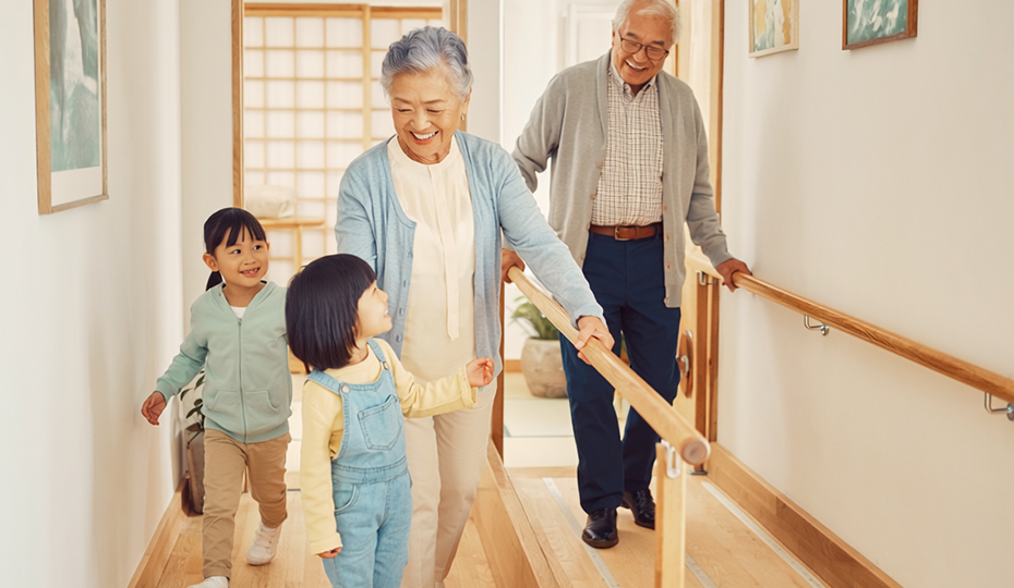 手すりのあるバリアフリー対応廊下を歩く老夫婦と子供