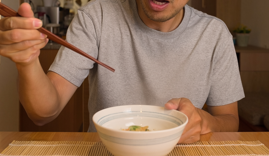 驚いた顔で箸を持つ人